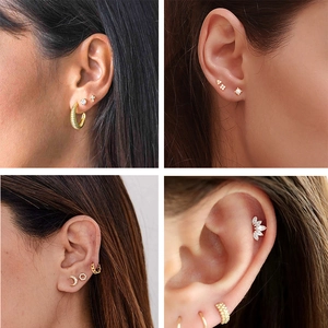 Close-up of 925 silver gold piercing studs with cross, moon, star and pearl details