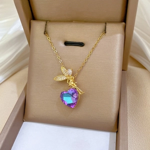 Macro detail of fairy pendant with purple heart crystal on golden necklace chain