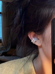 Detail of silver ear cuff with sparkling zircon floral clusters on model ear