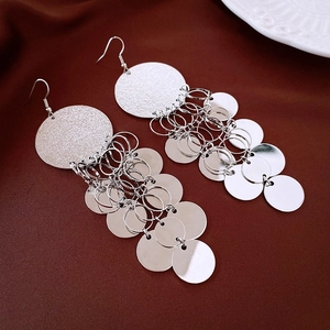 Detailed view of silver bow-knot tassel earrings with geometric round metallic plates