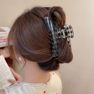 Detail view of large acrylic hair claw clip with black grey grid pattern on model hair