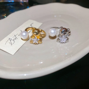 Close-up of gold and silver bear rings with star zircon and pearl on ceramic tray