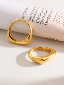 Macro shot of gold irregular twisted stainless steel rings on a minimalist background