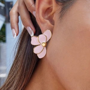 Detailed close-up of a pink floral earring with gold edges worn by a female model
