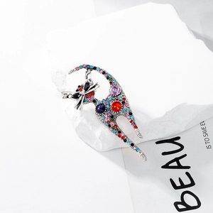 Macro detail of cat-shaped brooch with colorful rhinestones on a minimalist stone
