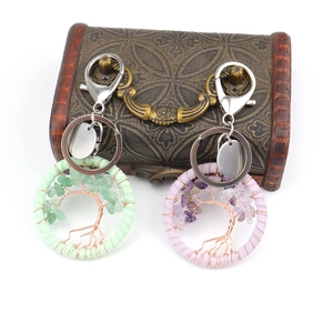 Handmade Tree of Life keychains with green and purple gemstones on a vintage wooden chest