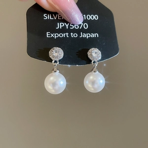 Close-up of geometric pearl earrings with shimmering cubic zirconia on silver studs