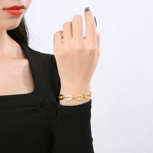 Close-up of a gold oval link chain bracelet worn on a wrist against a dark shirt