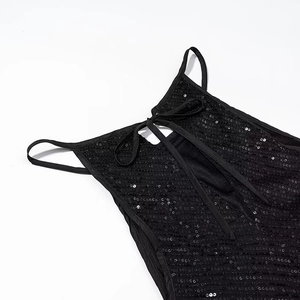 Detail of black sequined dress featuring back lace-up straps and shimmering texture