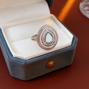 Détail macro d'une bague goutte en pierre bleu clair dans un écrin en velours