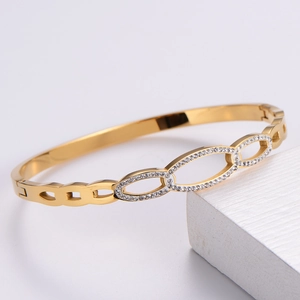 Macro detail of gold interlocking rings with sparkling crystals on an open bangle