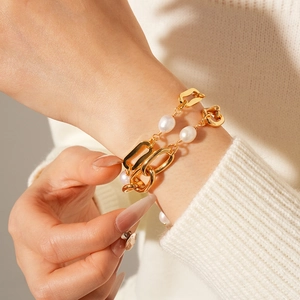 Detail of freshwater pearl and gold-plated chain bracelet set on woman's wrist