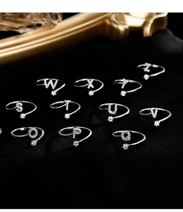 Detailed shot of silver initial rings with zircon star on black velvet background