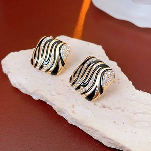 Details von Vintage-Ohrringen mit Zebra-Emaille und Kristallen auf beigefarbenem Stein