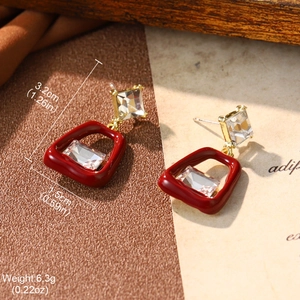 Detail showing dimensions of red enamel earrings with rhinestones on a vintage background