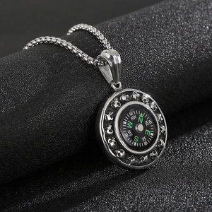 Macro shot of silver compass pendant with skull embossed details on stainless steel