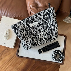 Detailed embroidery of floral and bird patterns on a black linen cosmetic storage bag