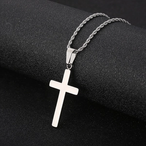 Macro detail of a polished silver stainless steel cross pendant and twisted rope chain