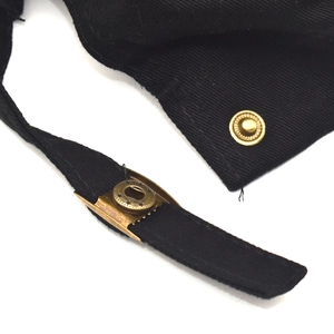 Detailed close-up of a vintage bronze metal snap button on black canvas baseball cap fabric