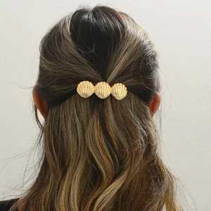 Elegant gold metal hair clip with three shell shapes on a minimalist half-up hairstyle