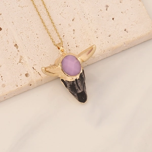 Detail of bohemian gold chain necklace with purple gemstone bull skull pendant