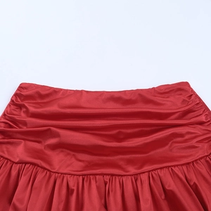 Detailed close-up of the red satin fabric showing intricate pleats and waistline texture