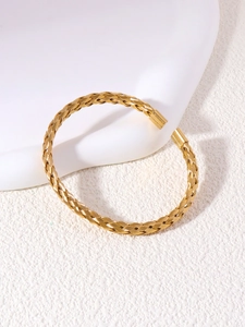 Detailed close-up of the woven gold texture and polished ends of the stainless steel cuff