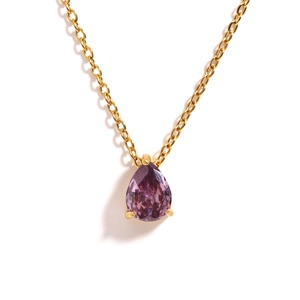 Macro shot of gold necklace with a prong-set pear-shaped purple gemstone on white background
