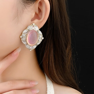 Close-up of vintage oval pink crystal earrings with gold trim on model ear