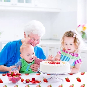 Pink strawberry print plastic tablecloth for girl birthday party in warm kitchen setting