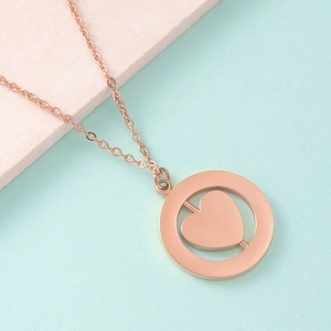 Macro shot of rose gold spinning heart pendant within a double circular ring necklace