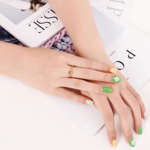 Detail of a minimalist gold knot ring shown on a model hand with a fashion magazine