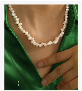 Elegant natural white pearl necklace worn on model neck with green satin blouse detail