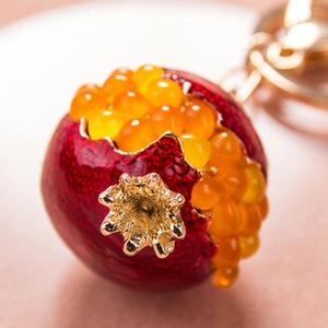 Detailed view of a pomegranate keychain with red enamel and sparkling orange rhinestones