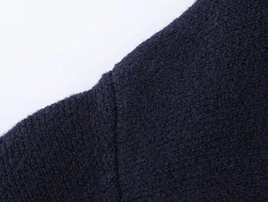 Macro shot of dark blue knit fabric showing texture and shoulder seam detail