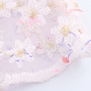 Broderie florale sur tulle blanc avec fil doré et détails de pétales pastel doux