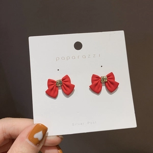 Close-up of red flocked bow earrings with silver posts and gold metallic accents