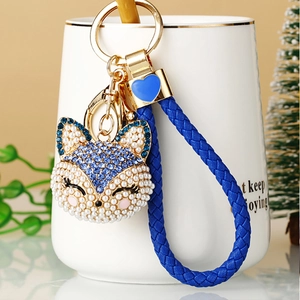 Detail of fox keychain with blue rhinestones, pearls and braided leather strap