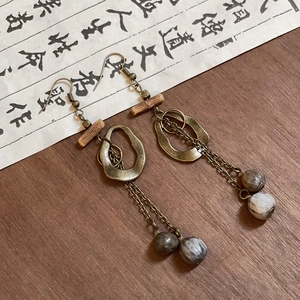 Detail of vintage handmade earrings with wooden beads and marble resin on wood surface