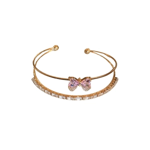 Elegant double-layered gold bangle featuring a pink zircon bow and pavé crystal bands