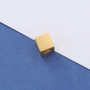 Macro shot of a golden square spacer bead with smooth surface on blue textured background