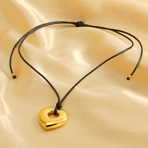 Golden hollow heart pendant necklace with adjustable black wax cord on champagne silk