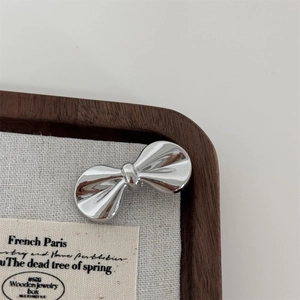 Close-up of polished silver bow-shaped metal hair clip on a premium wooden jewelry box