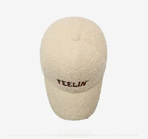 Detail view of beige teddy fleece baseball cap with brown FEELIN letter embroidery
