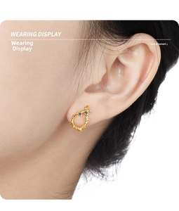 Close-up of golden irregular lava earring featuring three round blue gemstones on ear
