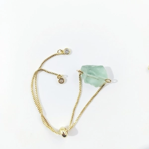 Detail of adjustable gold chain bracelet with raw green crystal and slide clasp
