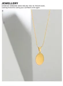 Macro shot of gold-plated oval pendant with bead chain on minimalist background