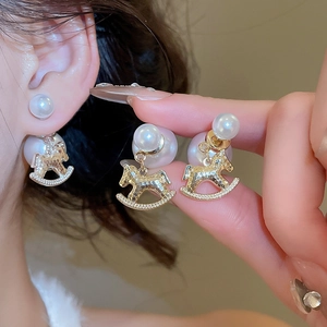 Detail of rocking horse earring with gold plating and double-sided faux pearls