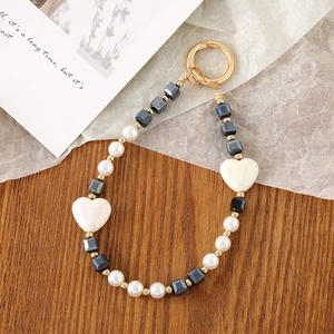 Detail of beaded phone strap with black square beads, white hearts and gold ring clasp