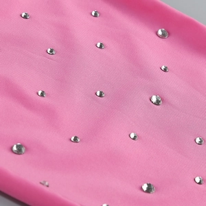 Macro shot of pink knit fabric with evenly spaced silver rhinestones on the short dress